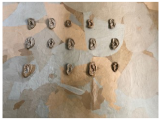 Das Bild zeigt eine Wand auf der einige Ohrmuscheln aufgeklebt sind.